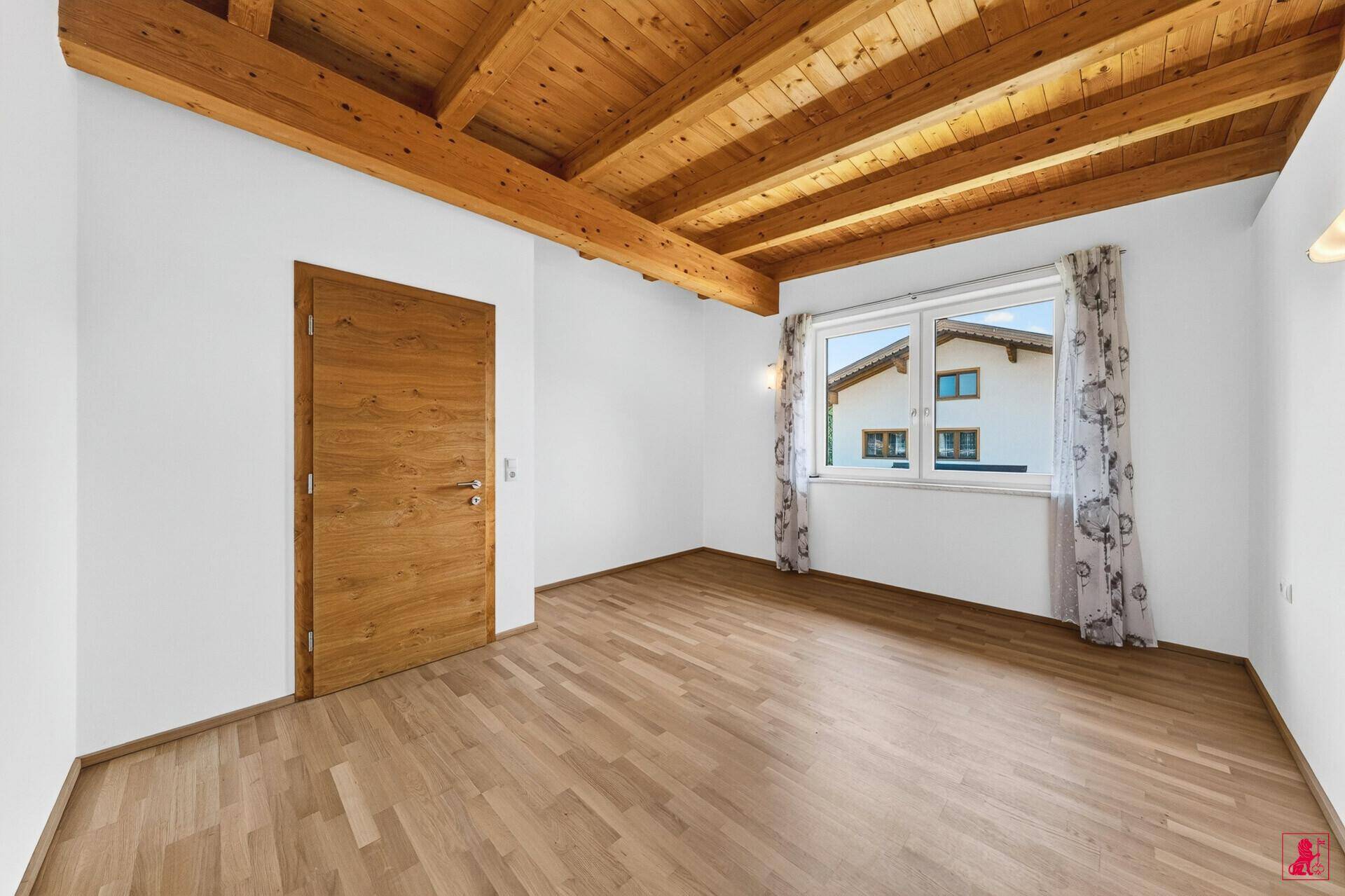 Geräumiges Schlafzimmer mit Holzbalkendecke, Parkettboden und Blick auf die Umgebung.
