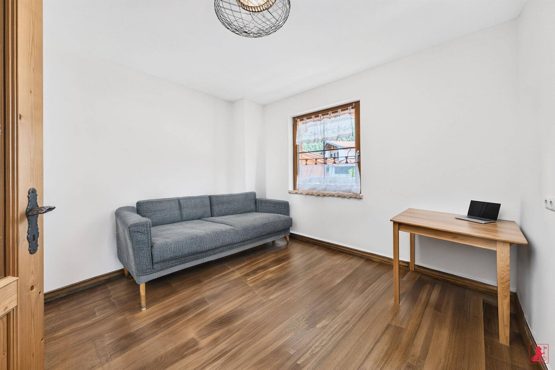 Helles Zimmer, eingerichtet als Büro oder Gästezimmer, mit Sofa und Schreibtisch.