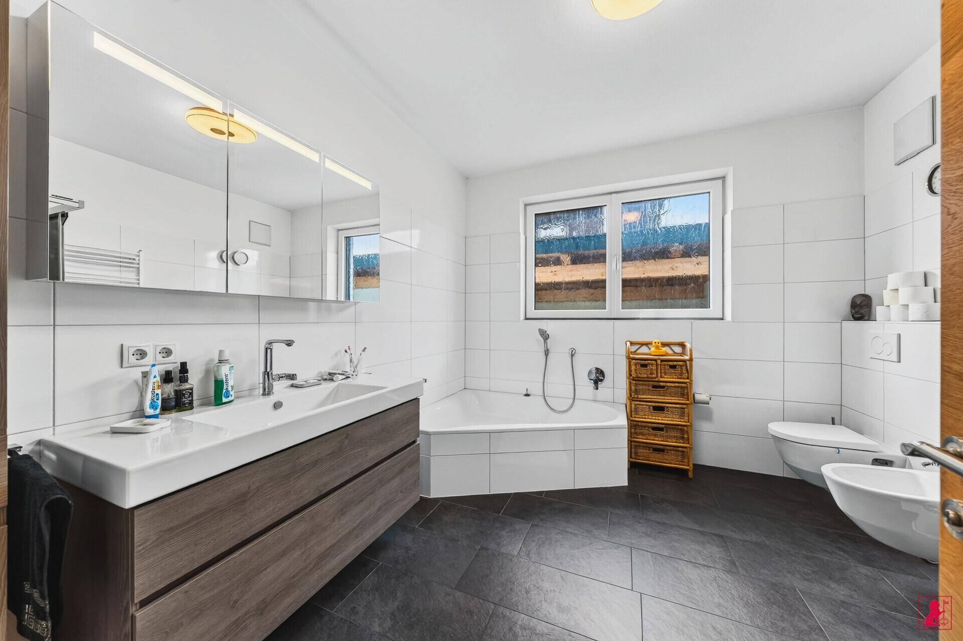 Modernes Badezimmer mit Badewanne, Doppelwaschbecken und Fenster.