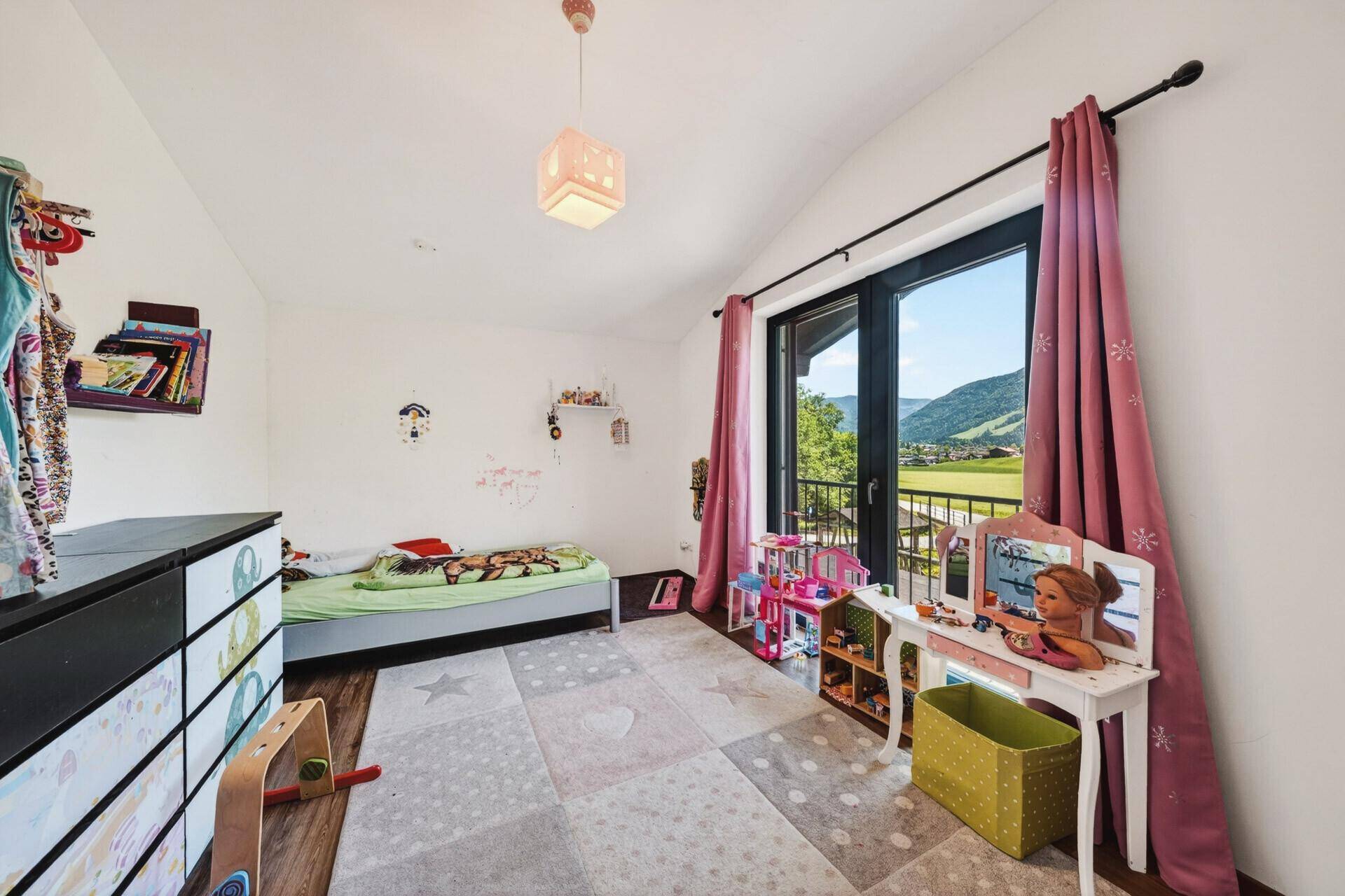 Mädchenzimmer mit Einzelbett, Schminktisch und Zugang zu einem französischen Balkon mit Bergblick.