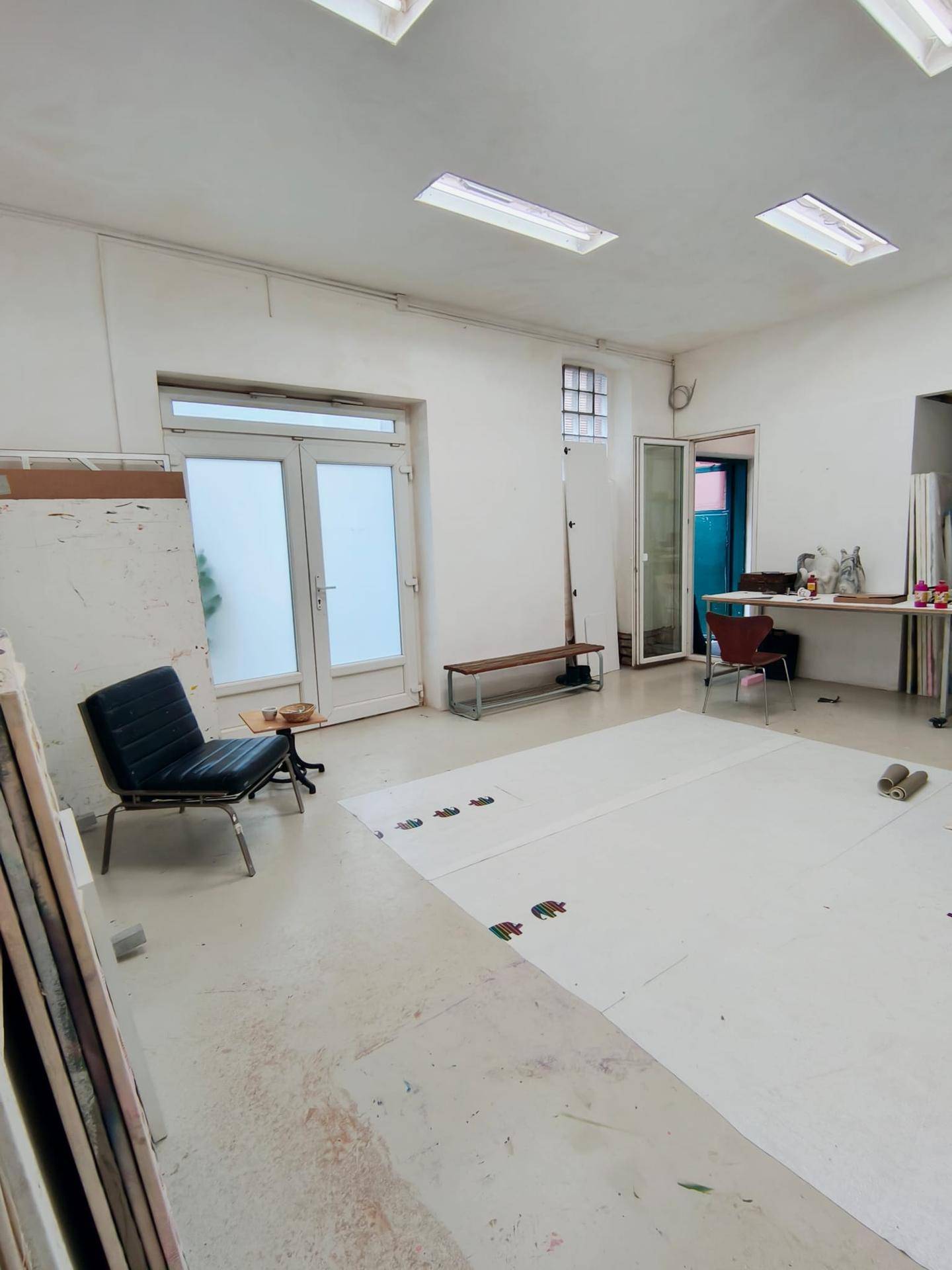 Helles und geräumiges Atelier mit hohen Decken, großen Fenstertüren und viel Platz zum Arbeiten.