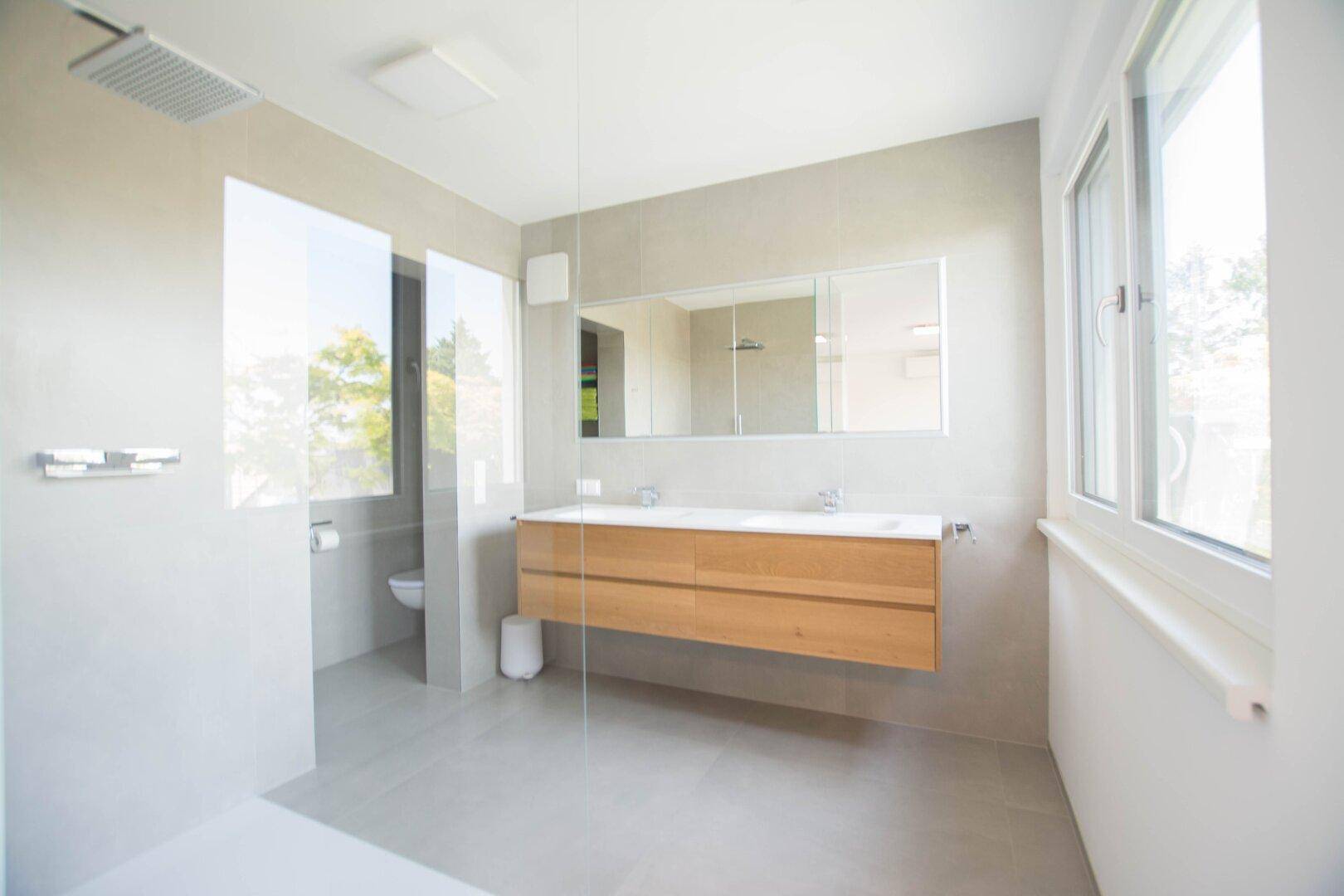 Modernes Badezimmer mit großer begehbarer Dusche, Doppelwaschbecken und Fenster.