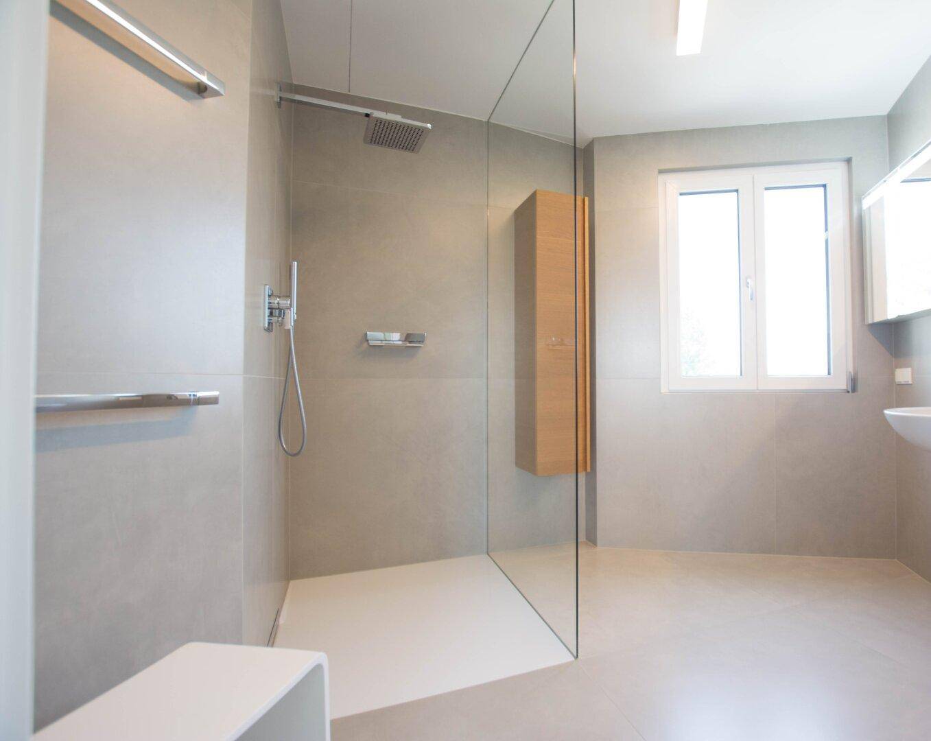 Helles Badezimmer mit begehbarer Dusche, kleinem Waschbecken und Fenster.