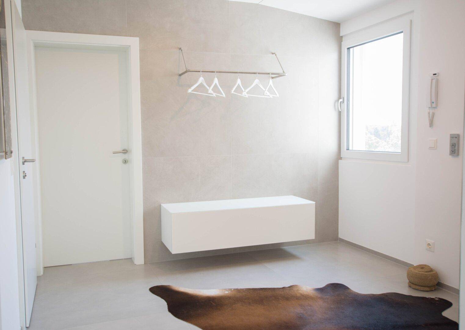 Heller Flur mit modernem Design, Fliesenboden und einem Fenster für Tageslicht.