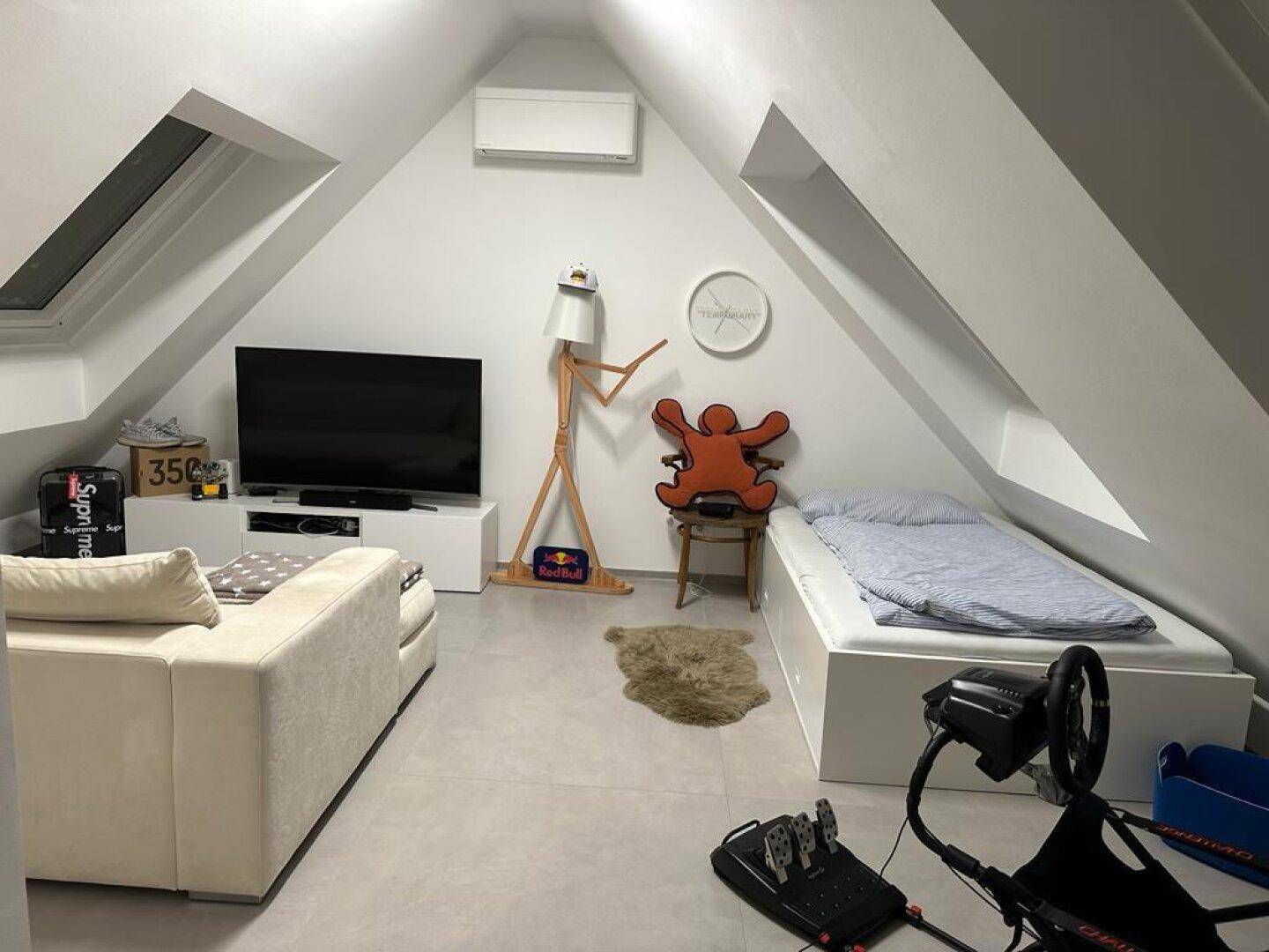 Vielseitiger Raum mit Dachschrägen, Bett, Sofa und Unterhaltungselektronik.