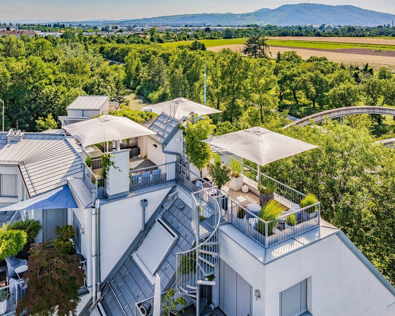 Moderne Wohnanlage mit mehreren Dachterrassen, Außenbereichen und Panoramablick auf die grüne Umgebung.
