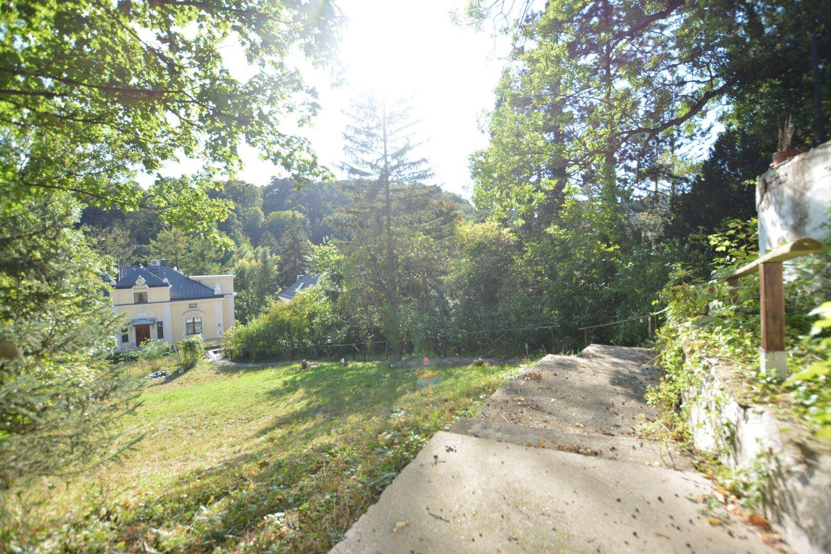 Sonnige Steintreppe im Gartenbereich mit weitem Blick auf die umliegende Landschaft und Gebäude.