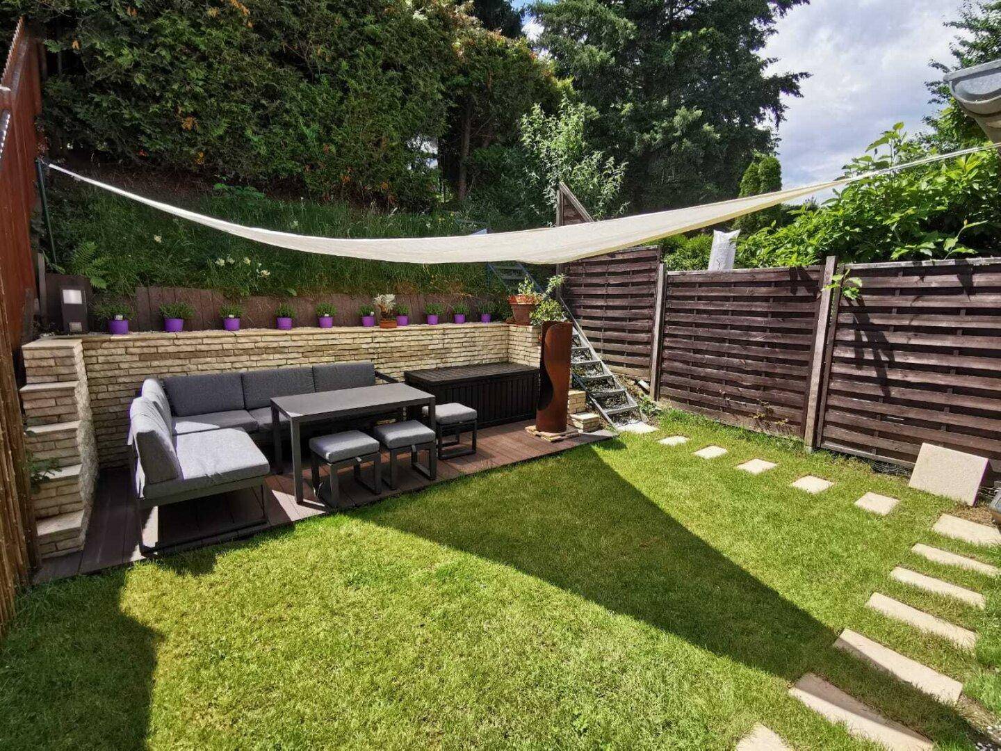 Sonniger Gartenbereich mit gemütlicher Sitzecke, Rasenfläche und Sichtschutz für entspannte Stunden.