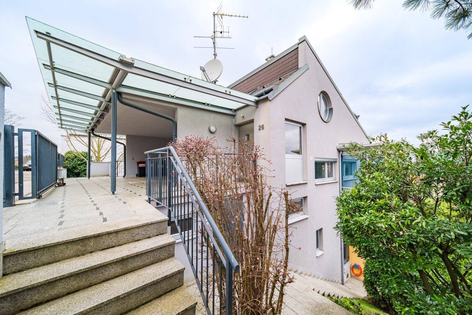 Eingangsbereich des Hauses mit Steintreppe, Glasüberdachung und modernem Design.
