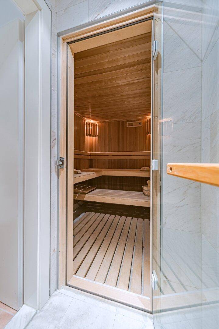 Moderne Holzsauna mit Bänken und stimmungsvoller Beleuchtung, ideal zur Entspannung.