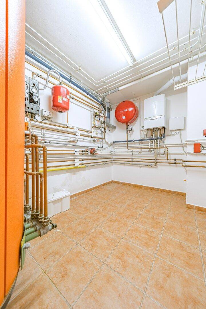 Technikraum mit Heizungsanlagen, Warmwasserspeichern und sichtbaren Rohrleitungen.