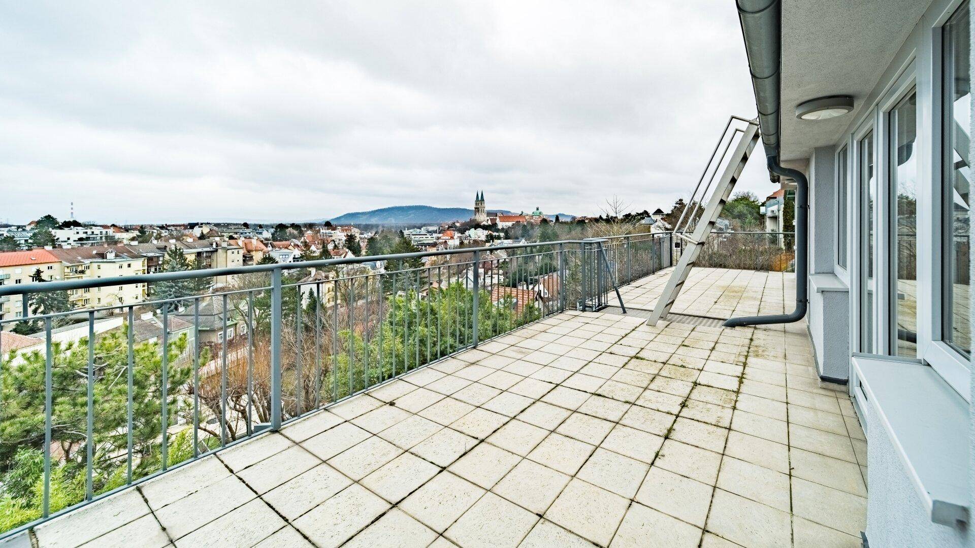 Große geflieste Terrasse mit weitem Blick über die Stadt und die umliegende Landschaft.