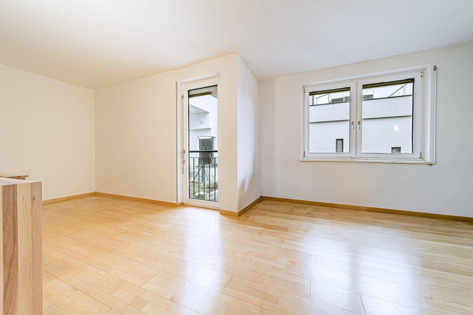 Heller Raum mit Holzboden und Fenster zum Innenhof, ideal als Schlaf- oder Arbeitszimmer.
