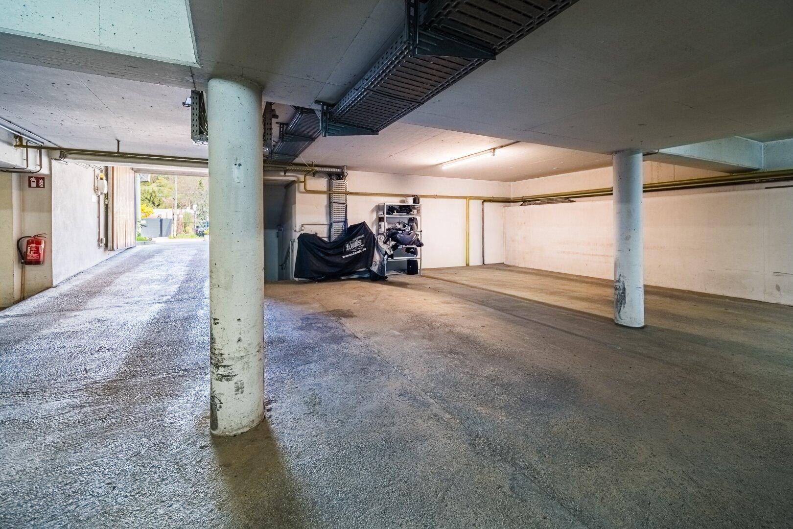 Tiefgarage mit Betonboden, Säulen und Zufahrt.