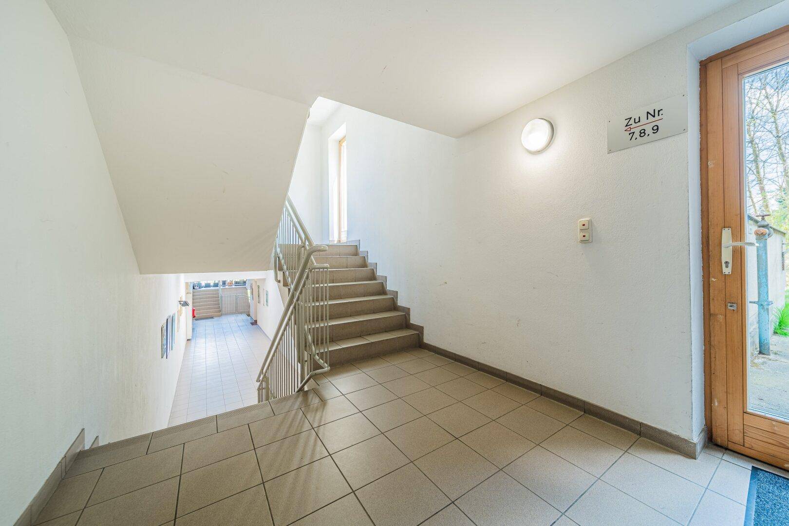 Treppenhaus mit Fliesenboden und Zugang zum Außenbereich.
