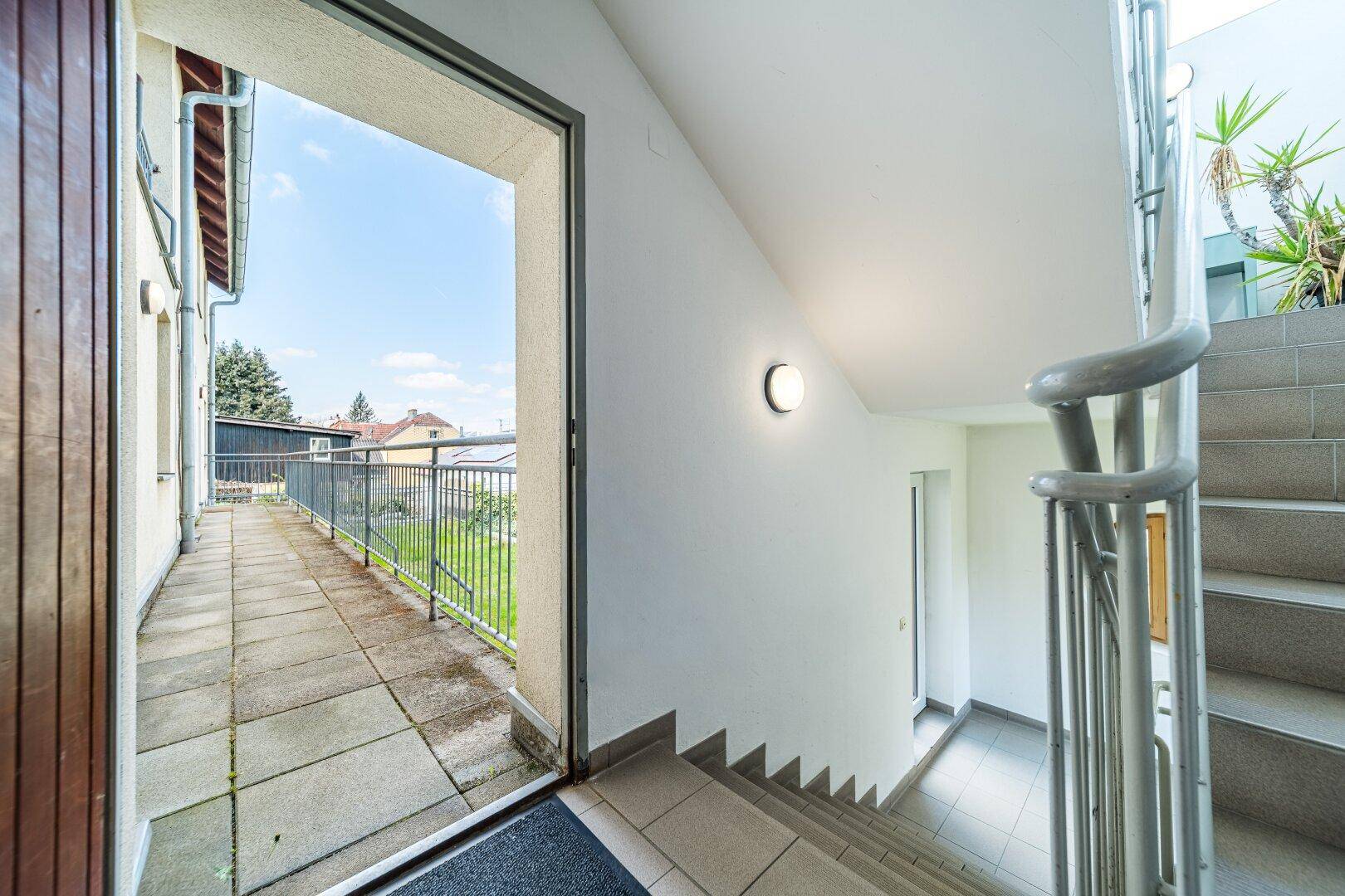 Treppenhaus mit Zugang zu einem Außenbereich und Blick ins Grüne.