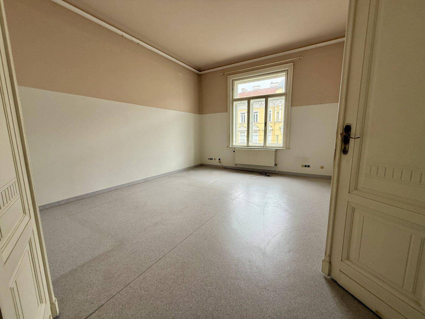 Geräumiger Büroraum mit Terrazzoboden und Stuckdecke, ideal für eine ruhige Arbeitsumgebung.