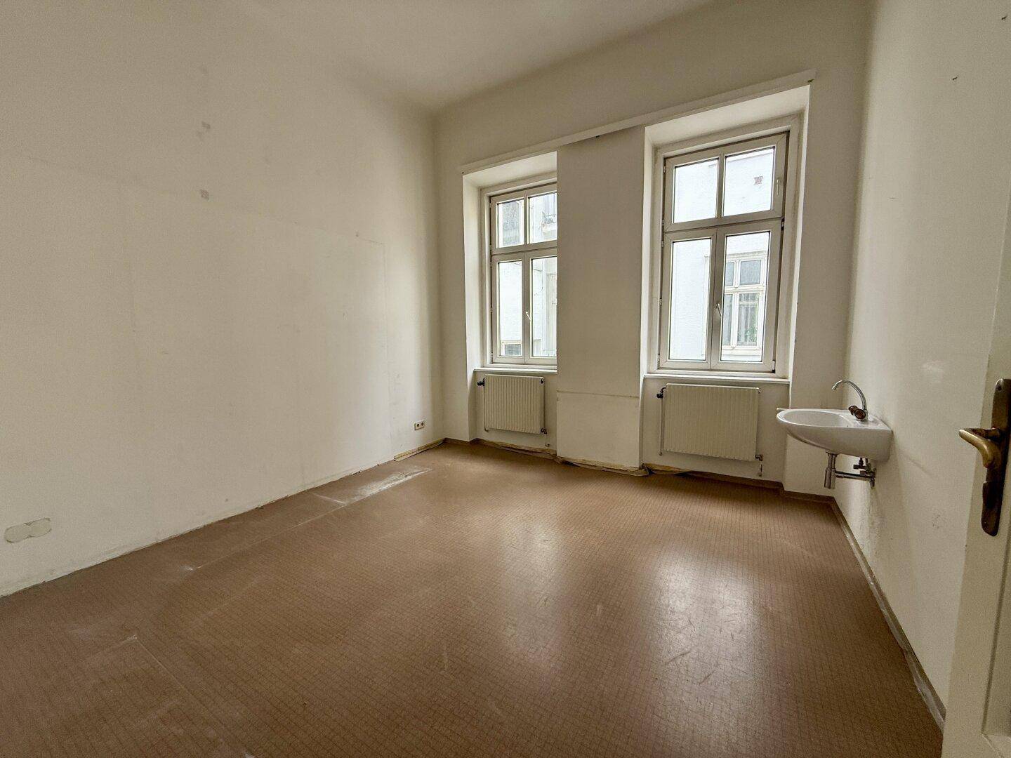 Kleiner Büroraum mit Waschbecken und zwei Fenstern, ideal für eine Praxis oder ein kleines Büro.