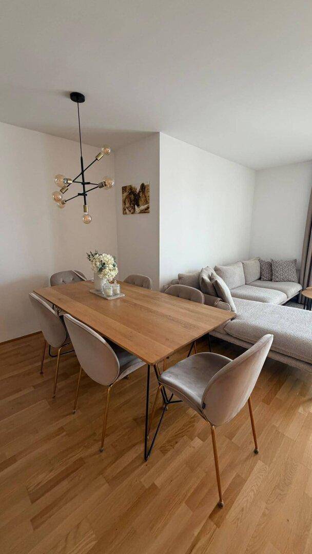 Offener Wohn- und Essbereich mit Holztisch, bequemen Stühlen und einem modernen Sofa.