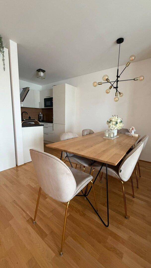 Essbereich mit Holztisch und modernen Stühlen, mit Blick auf die angrenzende Küche.