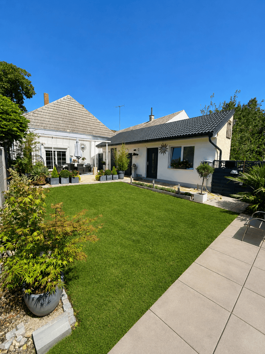 Gepflegtes Einfamilienhaus mit grünem Rasen und moderner Pflasterung im Garten.