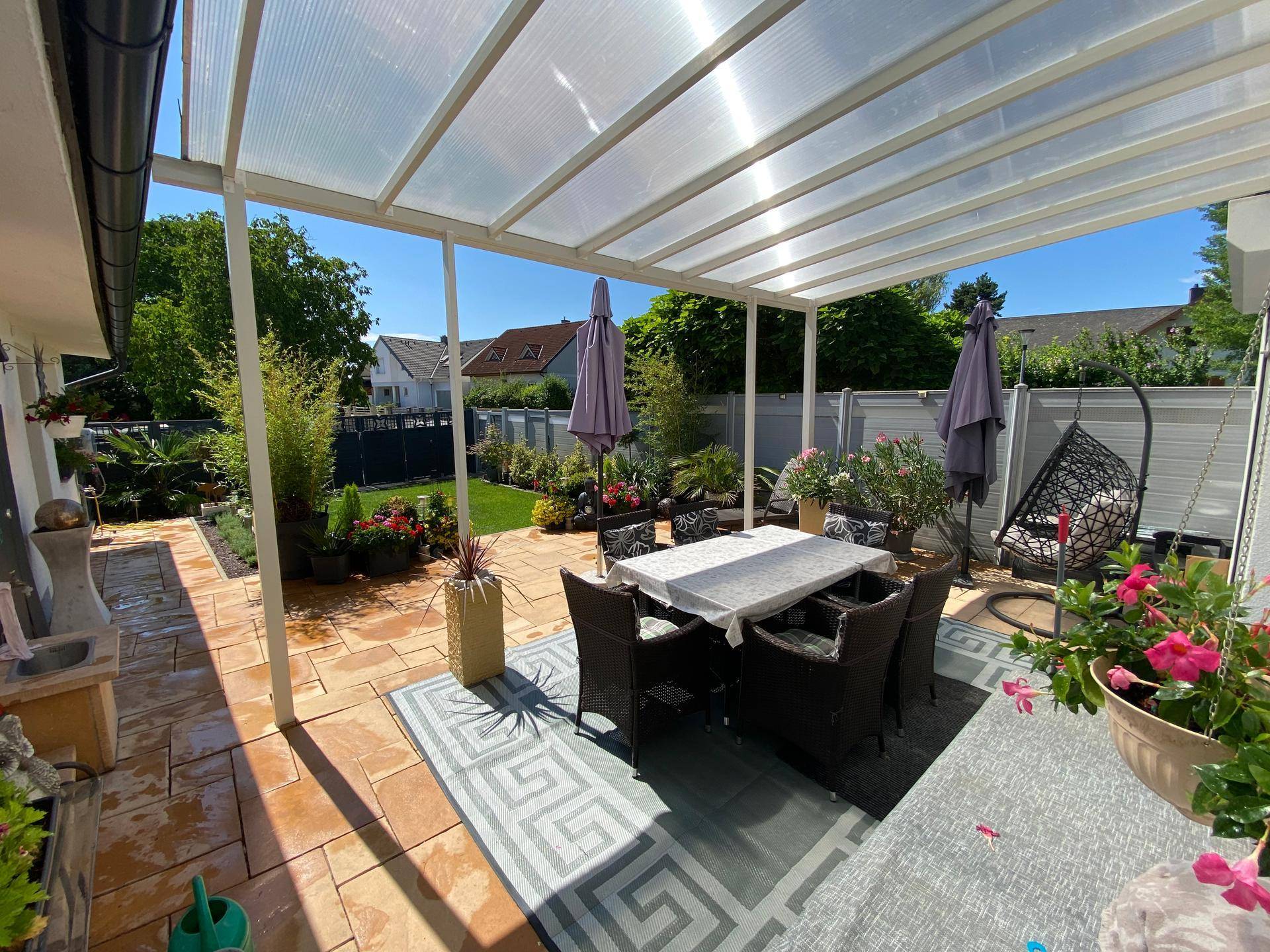 Überdachte Terrasse mit Esstisch und Sitzgelegenheiten, ideal für Mahlzeiten im Freien.