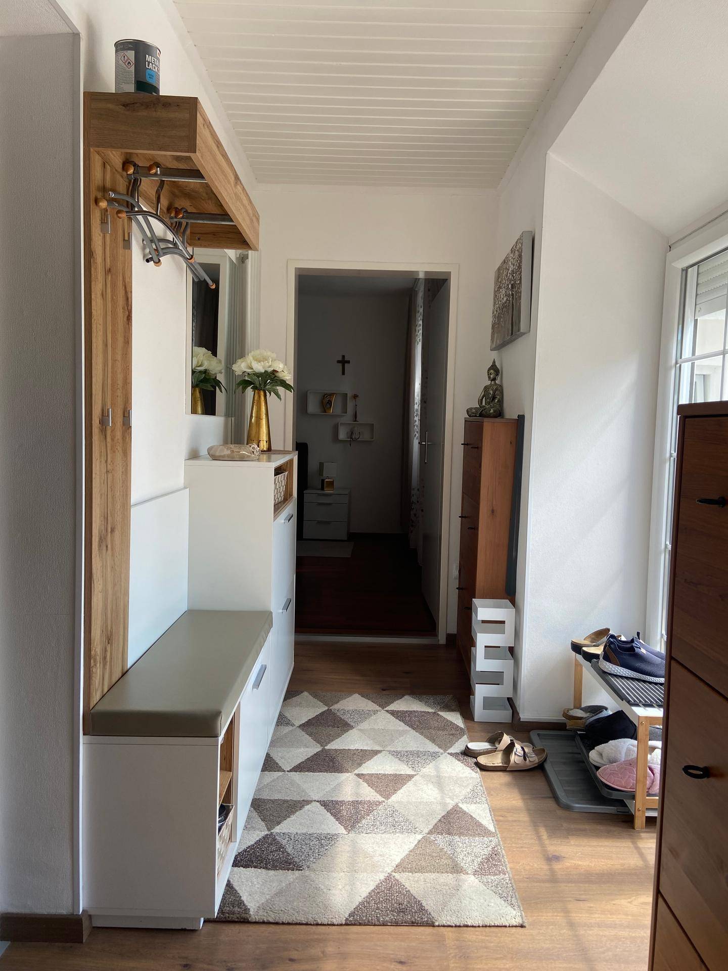 Heller Flur mit Garderobe, Sitzbank und praktischem Schuhregal auf Holzfußboden.