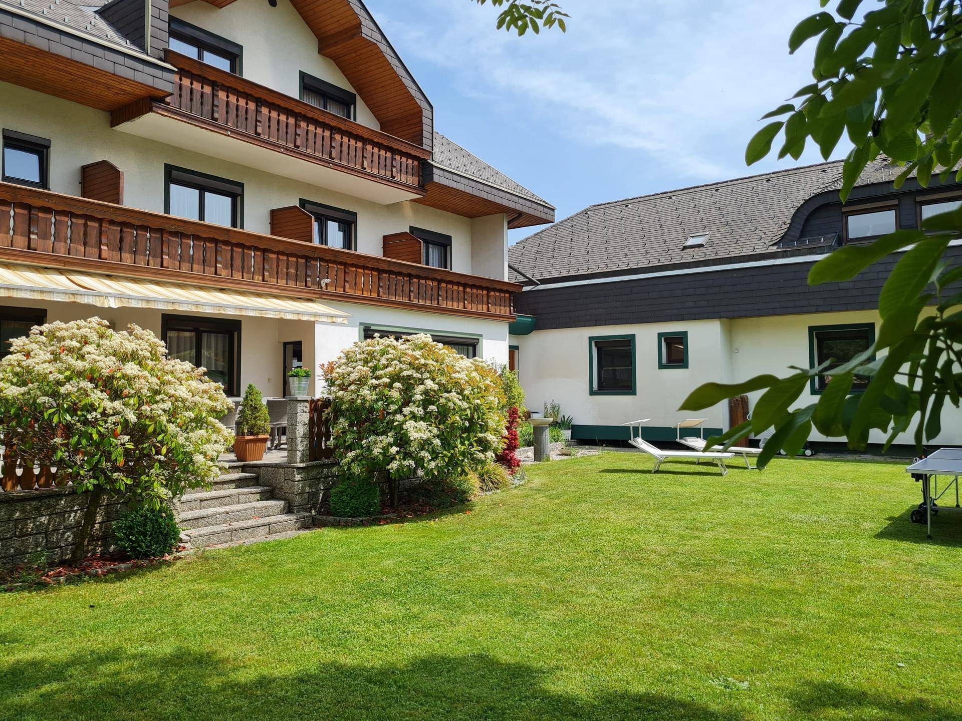 Gepflegter Gartenbereich mit Rasenfläche und blühenden Sträuchern vor dem Gebäude.