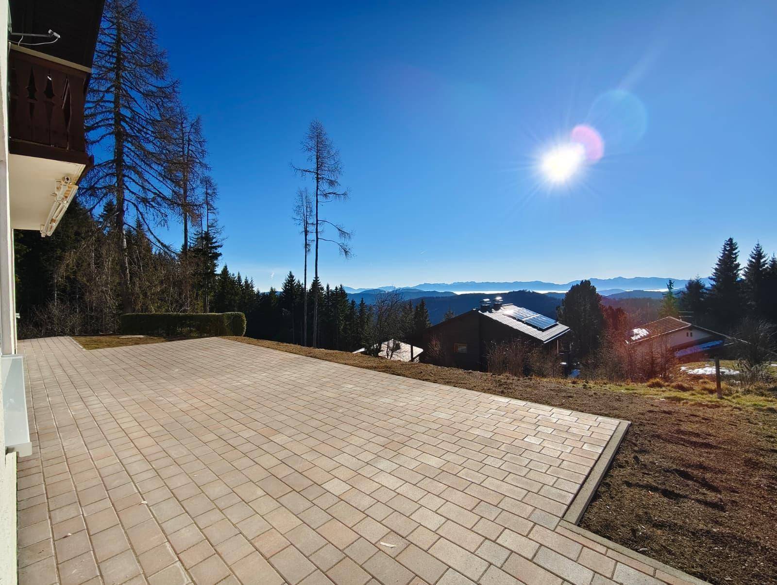 Große gepflasterte Terrasse mit sonnigem Bergblick, ideal für entspannte Stunden im Freien.
