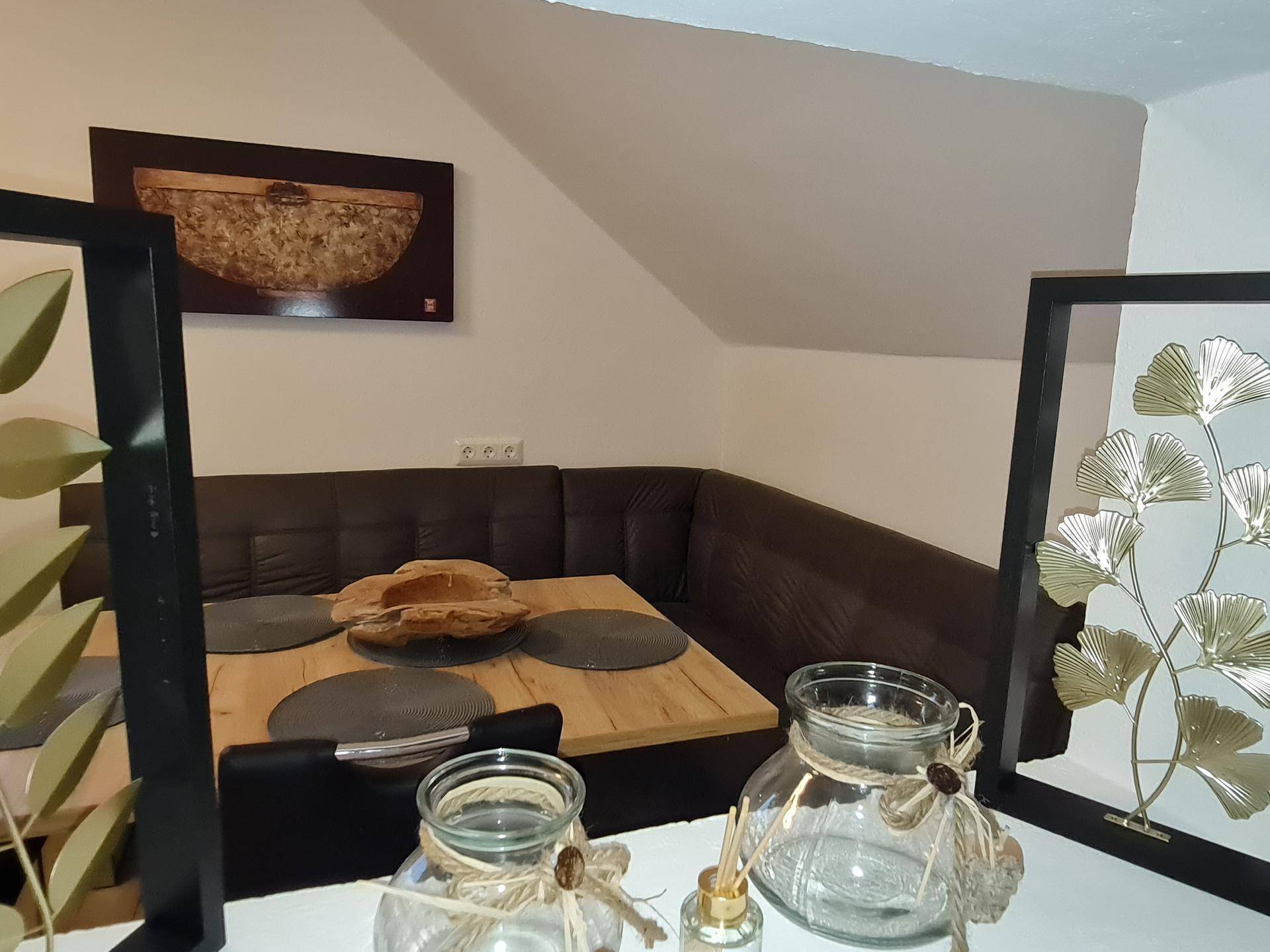 Gemütlicher Essbereich mit Eckbank, Holztisch und moderner Dekoration in warmen Farbtönen.