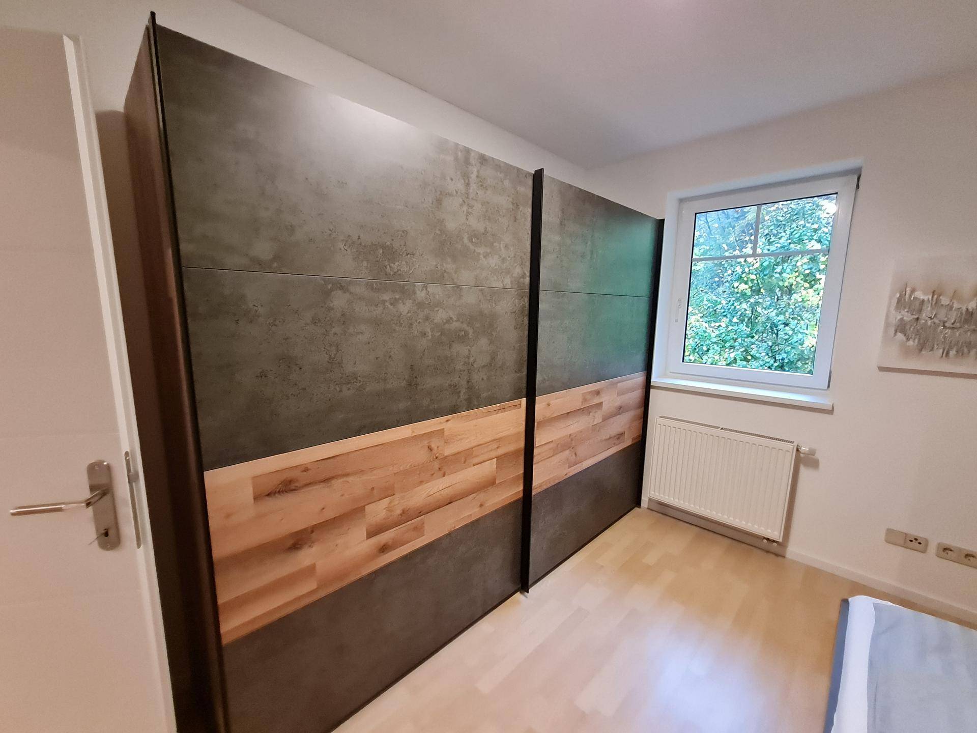 Großer, moderner Kleiderschrank mit Holz- und Betonoptik-Fronten im Schlafzimmer.