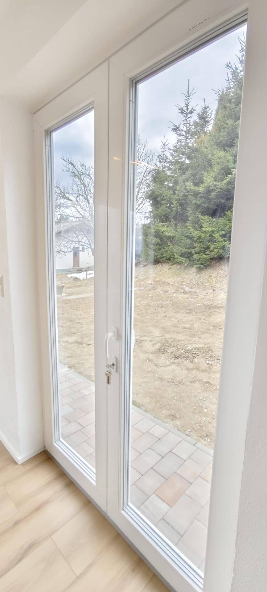 Große Glastür führt vom Innenraum direkt auf die gepflasterte Terrasse.