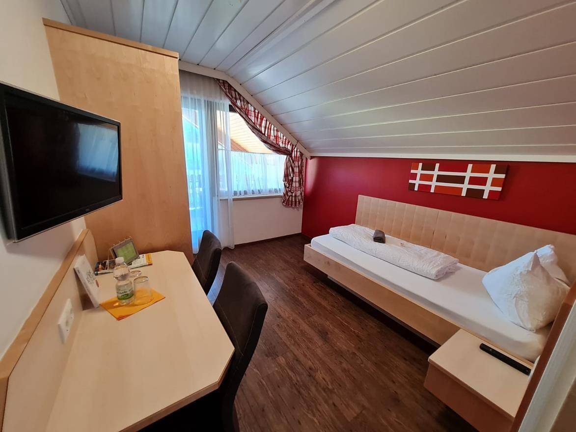 Komfortables Schlafzimmer mit Doppelbett, Teppichboden und Balkonzugang mit Bergblick.