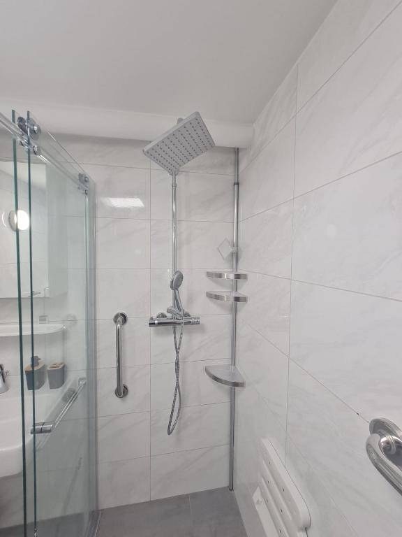 Detaillierte Ansicht der modernen, barrierefreien Dusche mit Regenduschkopf und Haltegriffen.