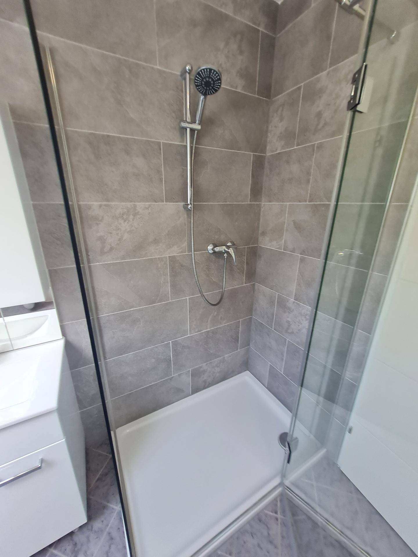 Geräumige Duschkabine mit Glaswand und modernen grauen Fliesen im Badezimmer.