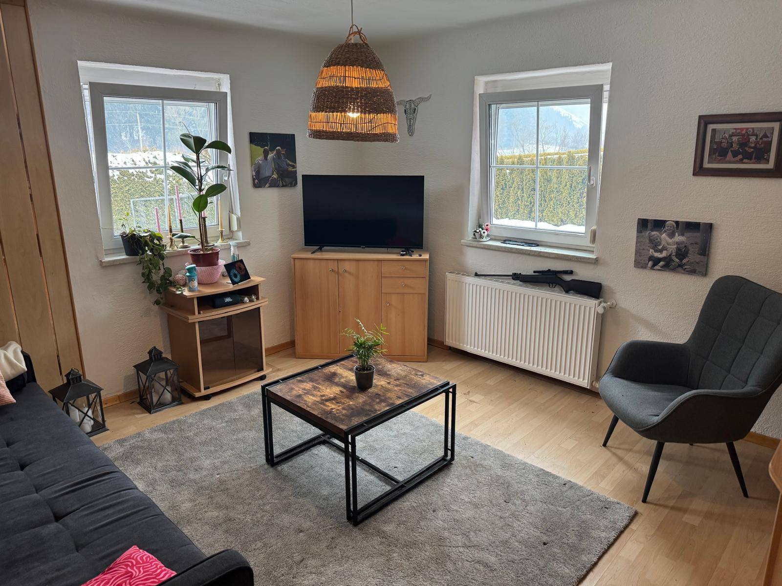 Gemütliches Wohnzimmer mit Sofa, Couchtisch und zwei Fenstern für natürliches Licht.