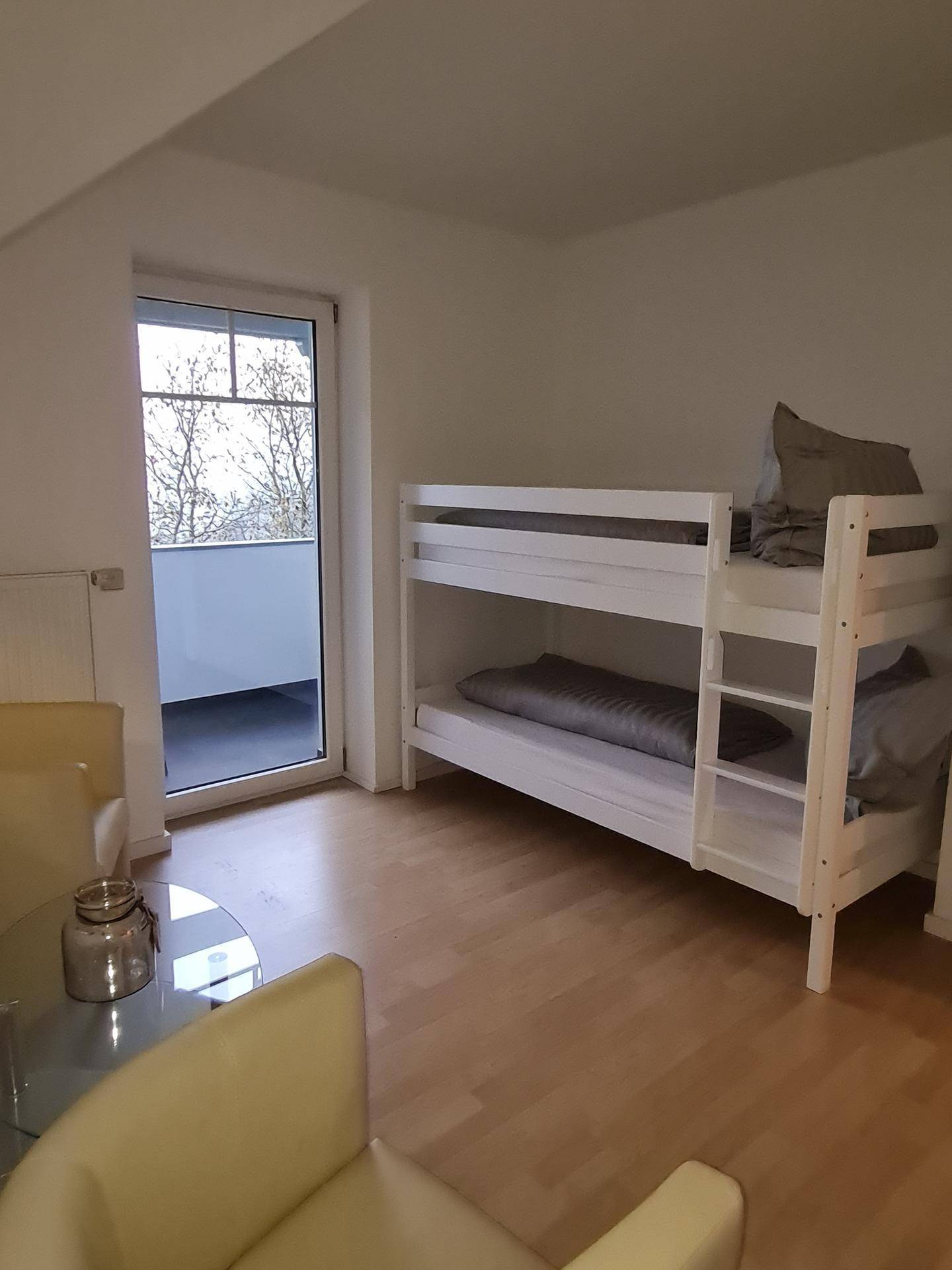 Schlafzimmer mit Etagenbett, bequemen Sesseln und Zugang zu einem Balkon oder einer Terrasse.