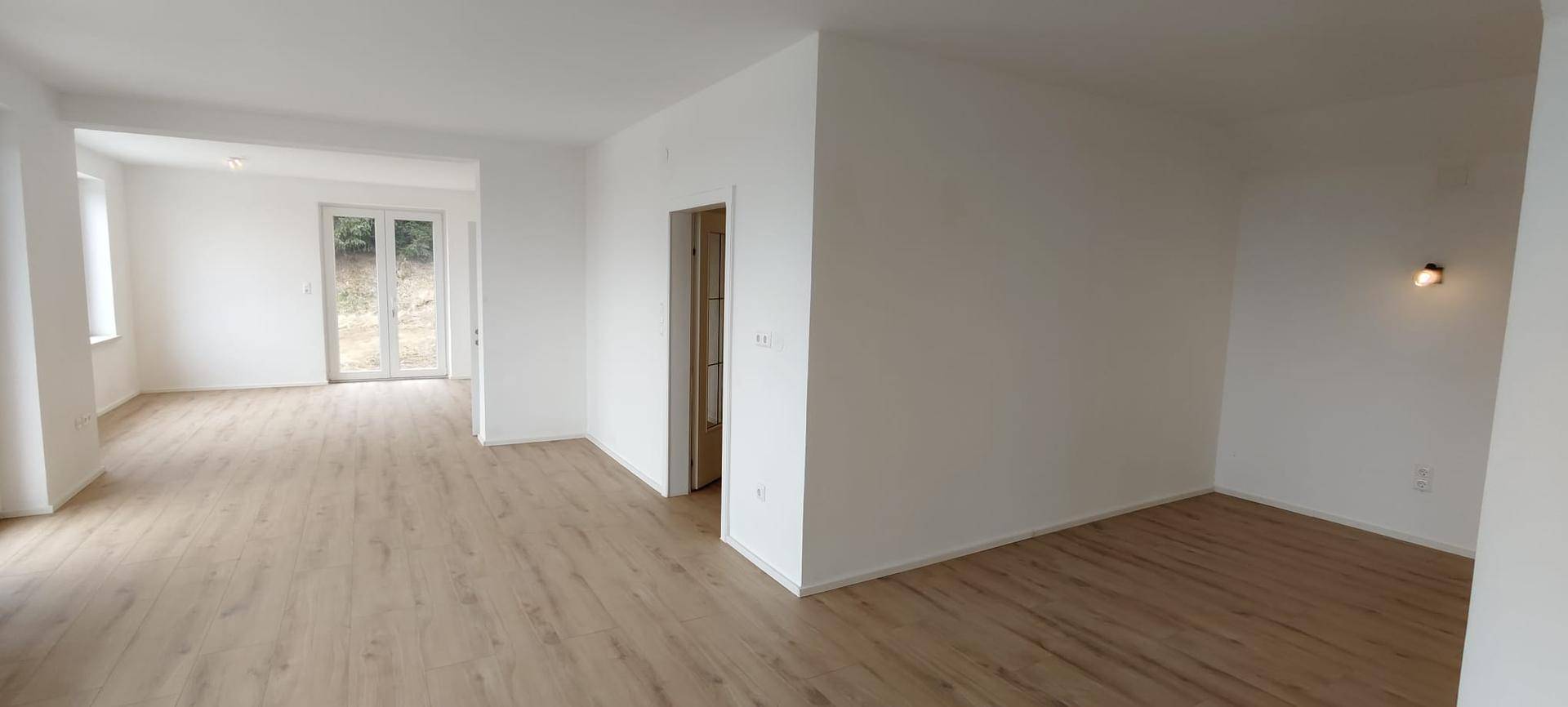 Geräumiger, heller Wohnbereich mit Laminatboden und Zugang zur Terrasse.