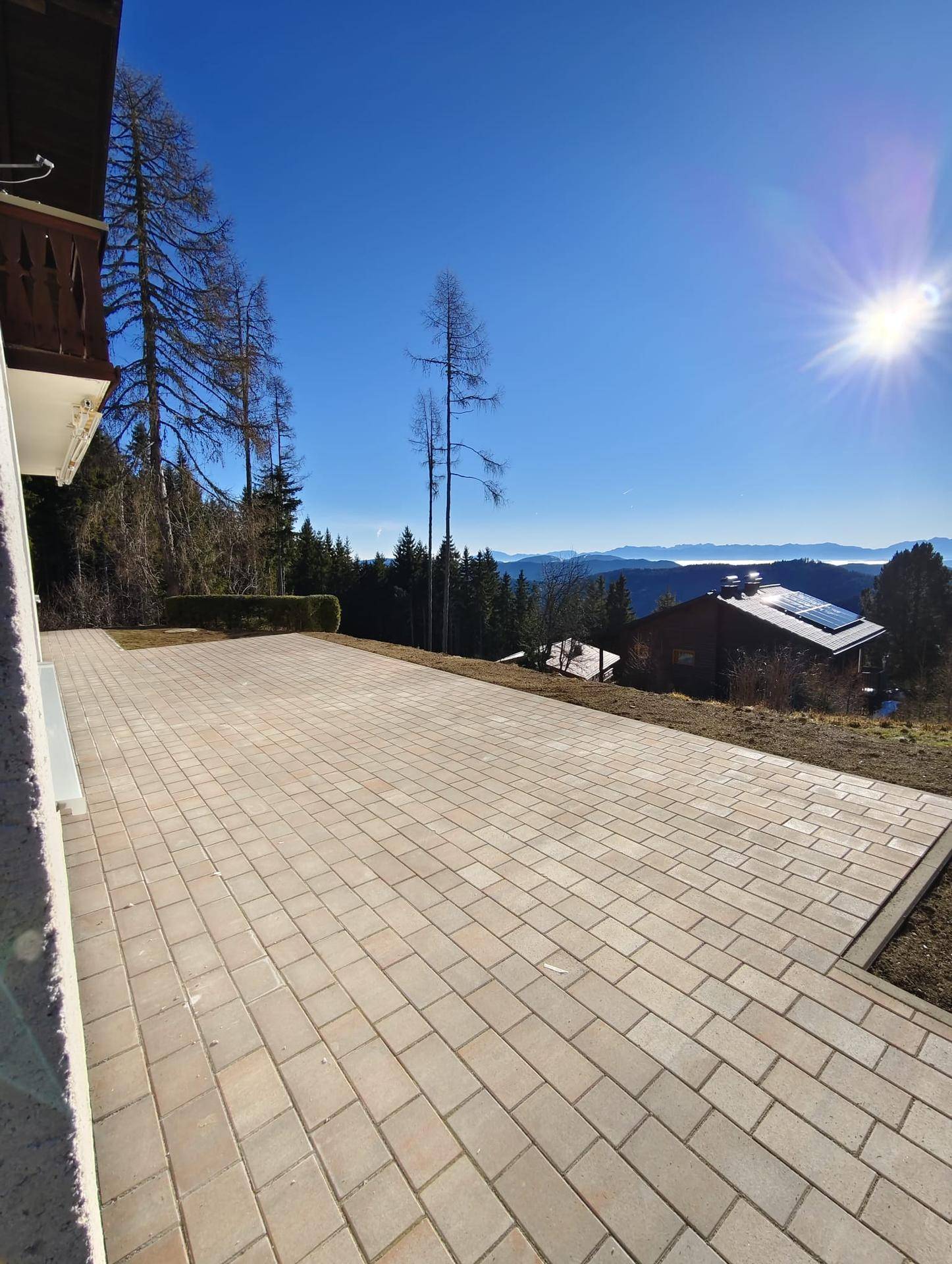 Weitläufige gepflasterte Terrasse mit sonnigem Bergblick, ideal für Outdoor-Aktivitäten.