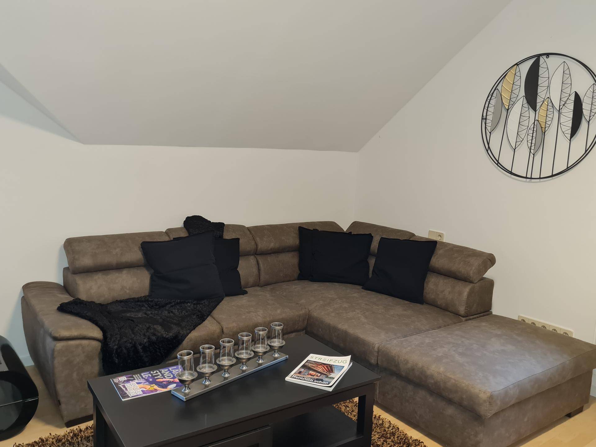 Gemütliches Wohnzimmer mit großem Ecksofa, Couchtisch und moderner Wanddekoration.