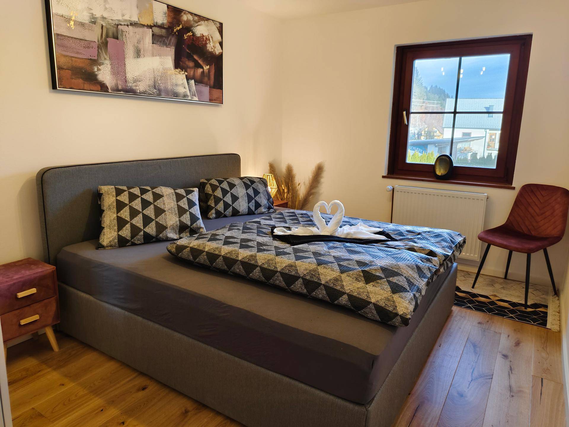 Helles Schlafzimmer mit komfortablem Bett, Nachttisch und Blick auf die umliegende Landschaft.