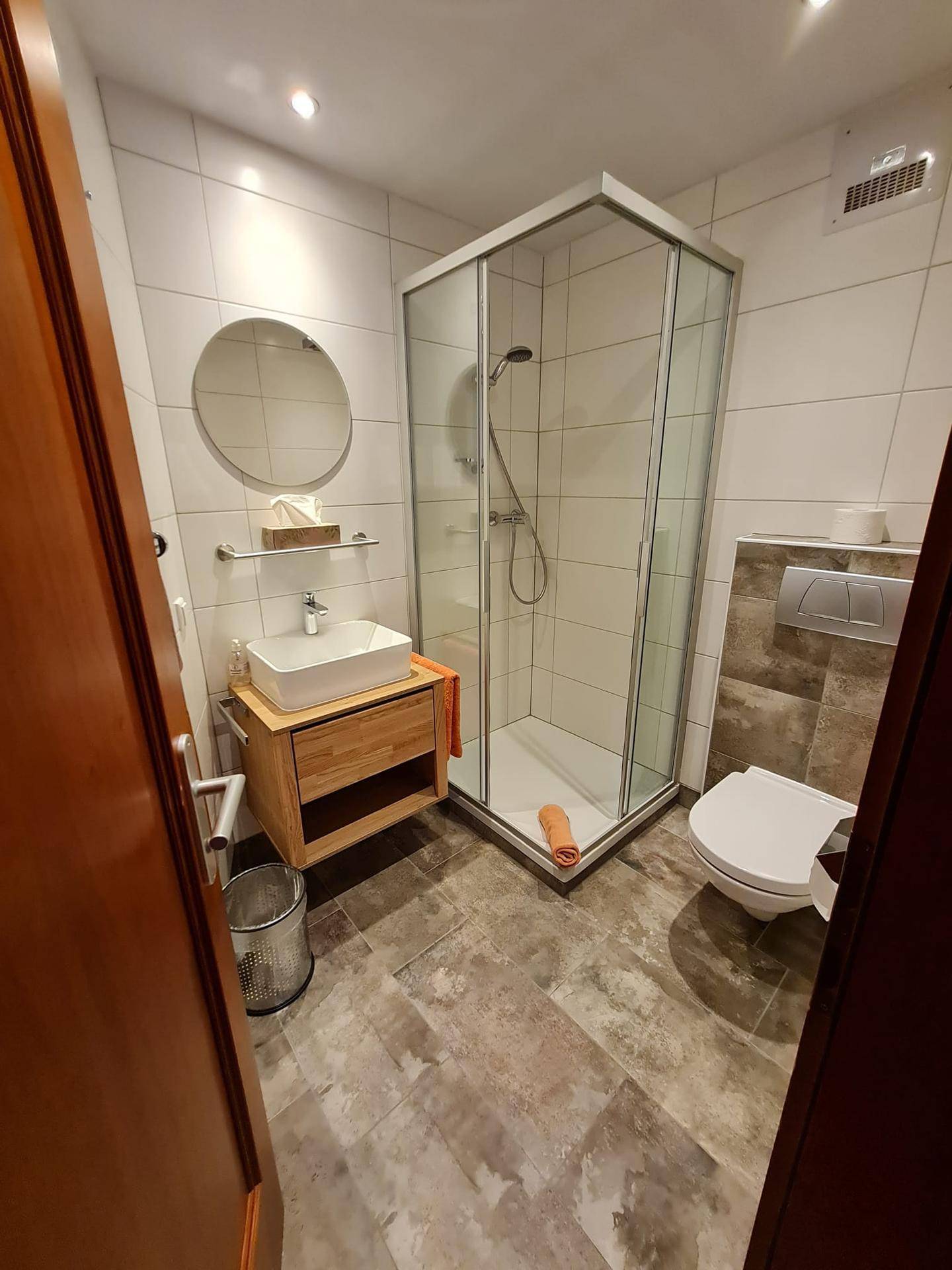Modernes Badezimmer mit Duschkabine, wandhängendem WC und stilvollem Waschbecken.