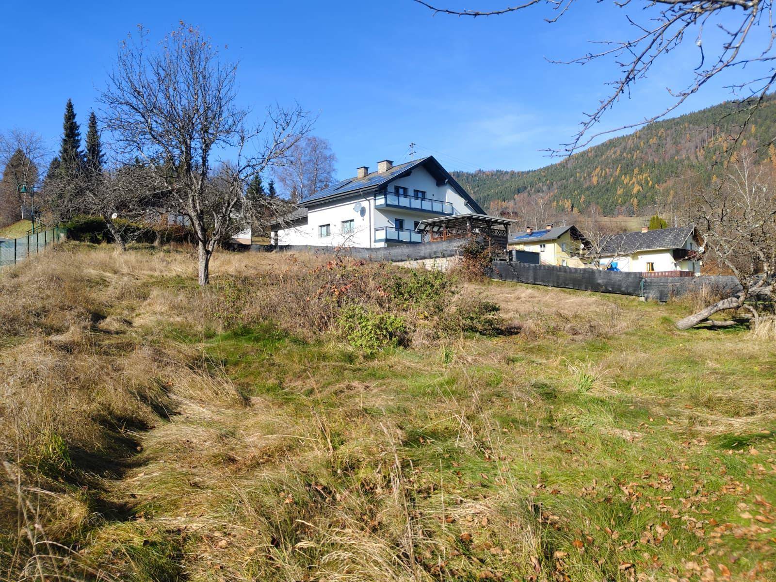 Weitläufiges Grundstück mit einem Wohnhaus im Hintergrund und bewaldeten Hügeln.