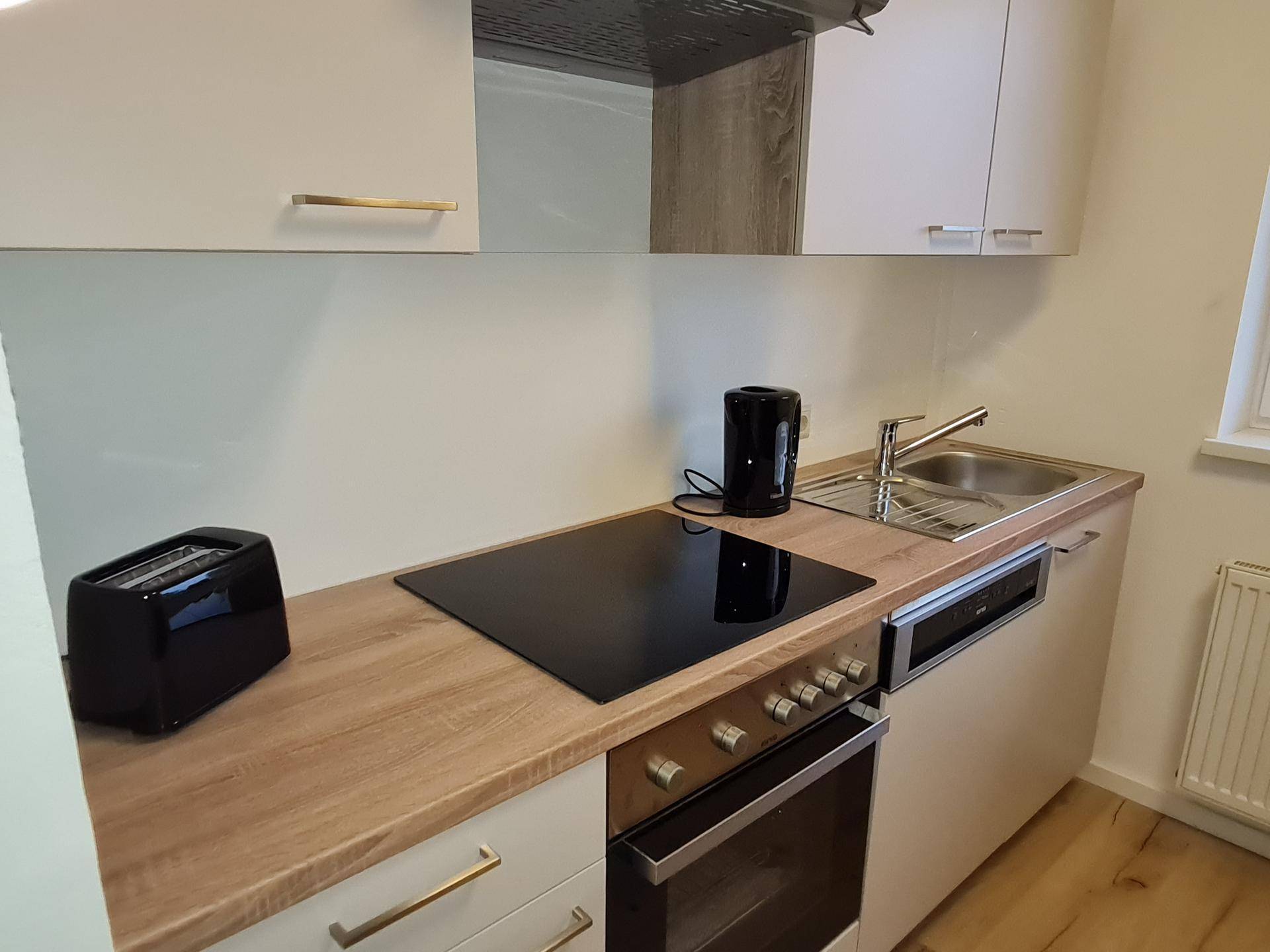 Detailansicht der Küchenzeile mit Induktionskochfeld, Spüle und modernen Küchengeräten.