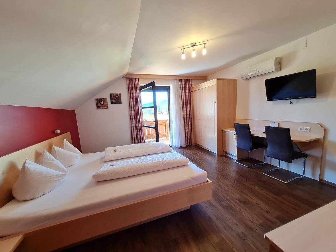 Helles Schlafzimmer im Dachgeschoss mit Doppelbett, Schreibtisch und Klimaanlage.