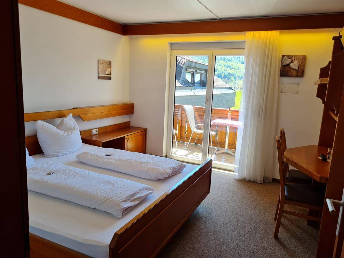 Rustikales Schlafzimmer im Dachgeschoss mit Holztäfelung, Doppelbett und Teppichboden.