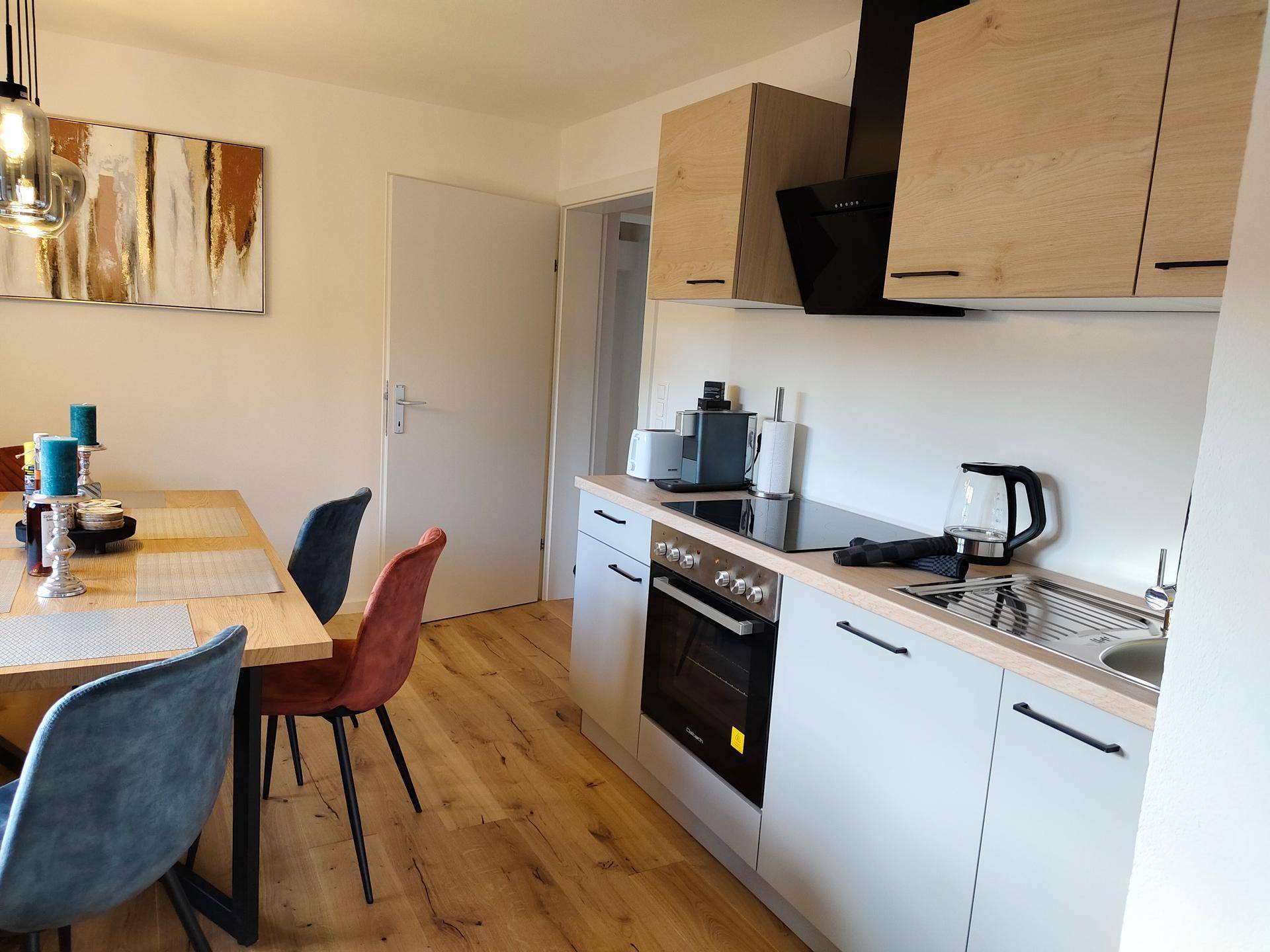 Moderne Einbauküche mit hellem Holzdekor und Essbereich, ausgestattet mit Induktionskochfeld und Backofen.