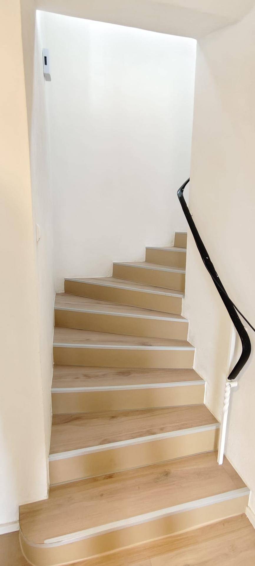 Moderne Holztreppe mit hellem Geländer, die die verschiedenen Etagen des Hauses verbindet.