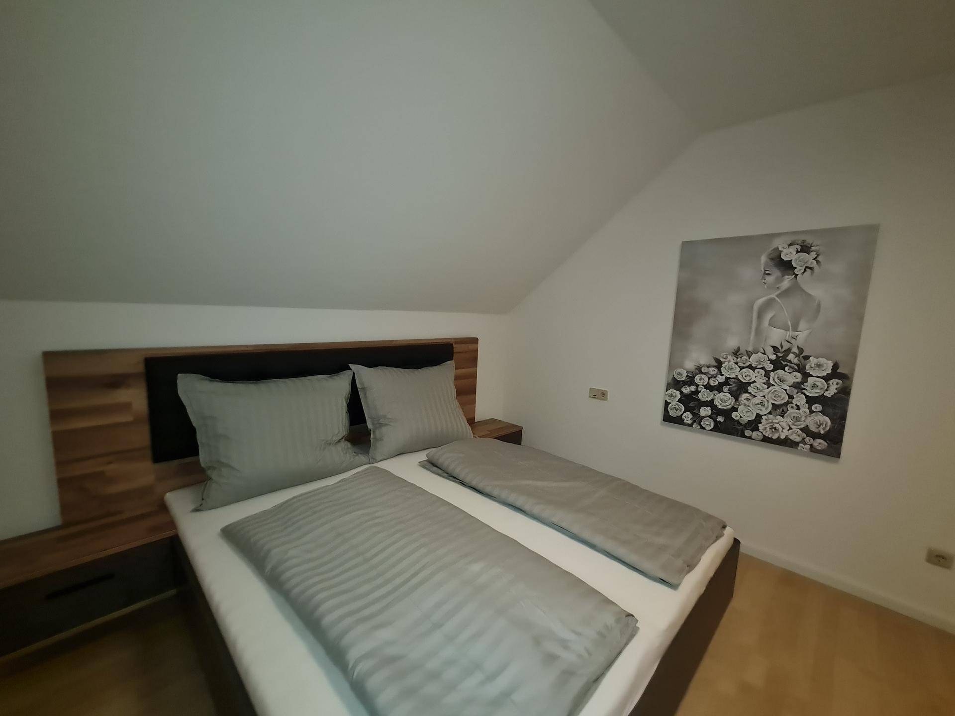 Gemütliches Schlafzimmer mit Doppelbett und schräger Decke, ideal für erholsame Nächte.