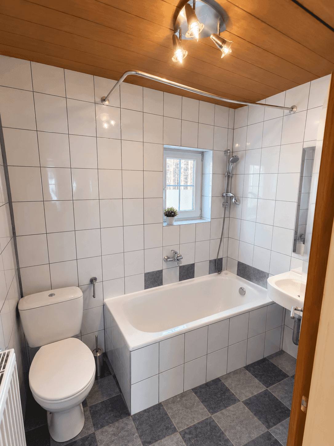 Ordentliches Badezimmer mit Badewanne, Duschvorhangstange, Toilette und Fenster für natürliche Belüftung.